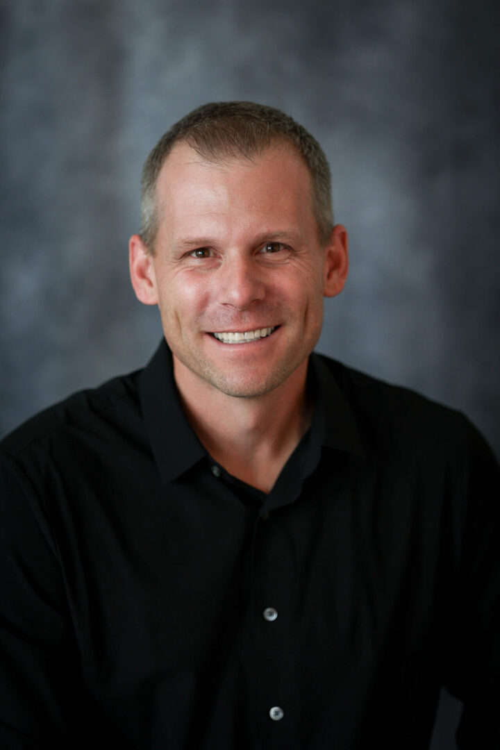 A man in black shirt smiling for the camera.